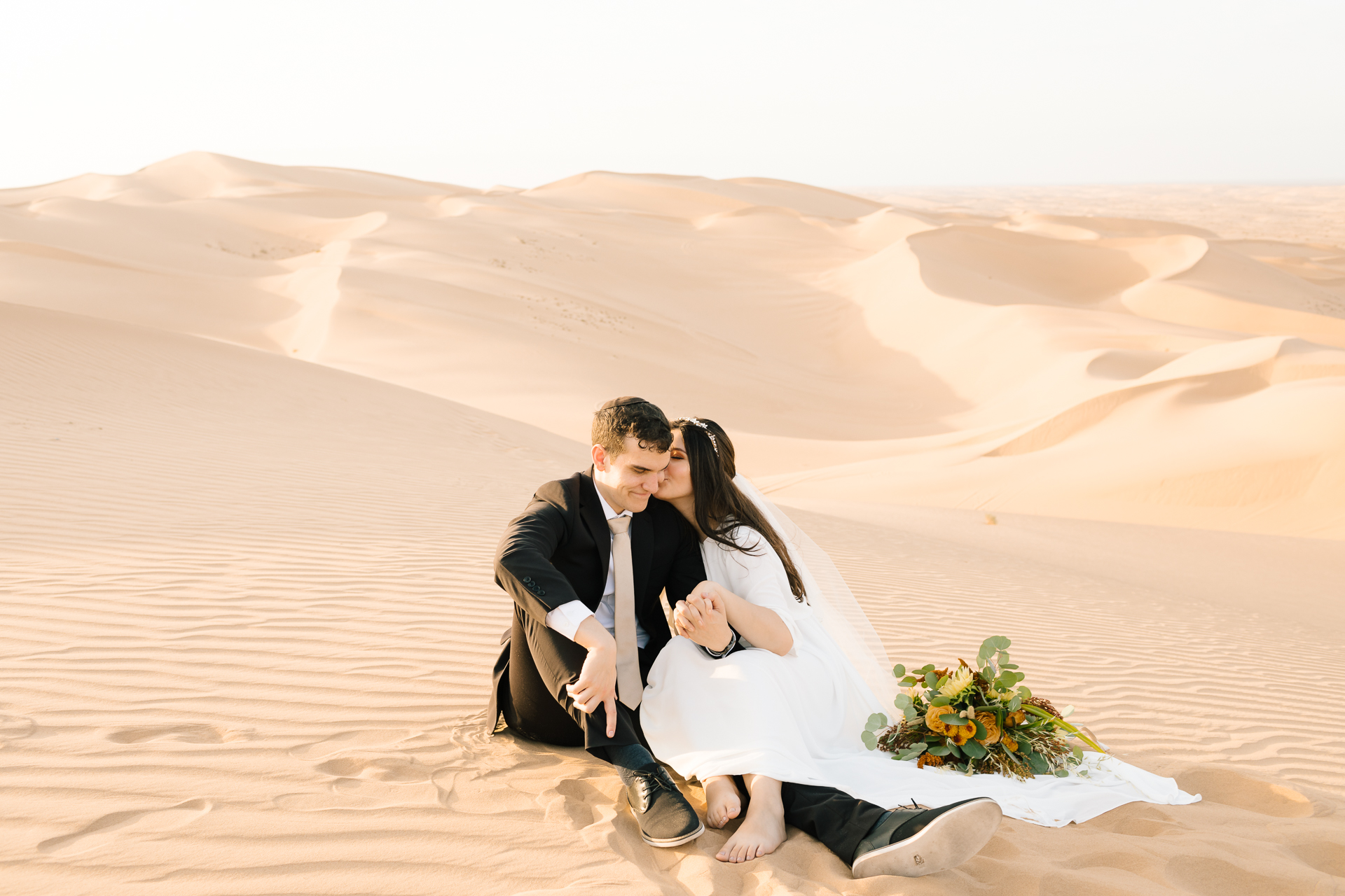 bride and groom sitting at glamis sand dunes