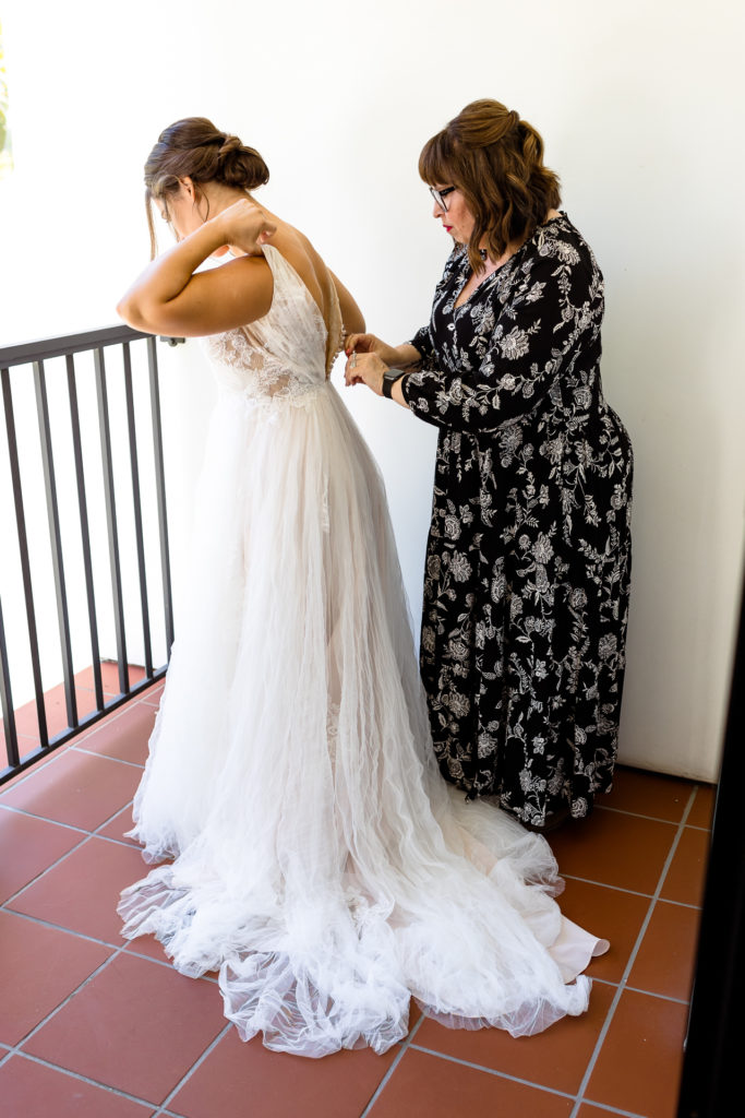 mom zipping bride into her wedding gown